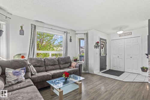 Living area featuring wood-finish flooring, white walls, and a large picture window - 128 Brookview Wy, Stony Plain, AB 