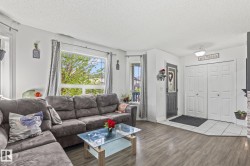 Living area featuring wood-finish flooring, white walls, and a large picture window - 