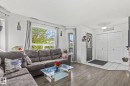 Living area featuring wood-finish flooring, white walls, and a large picture window - 128 Brookview Wy, Stony Plain, AB 