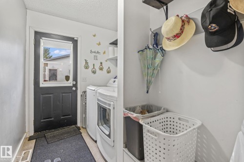 Laundry area with white walls and a dark paneled door featuring a window - 128 Brookview Wy, Stony Plain, AB 