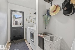 Laundry area with white walls and a dark paneled door featuring a window - 