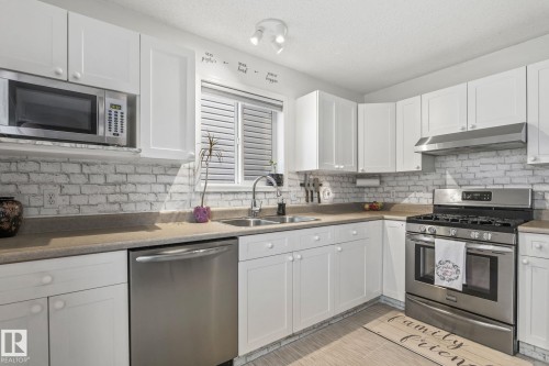 Kitchen featuring white cabinetry and stainless steel appliances, including a built-in microwave, gas range, and dishwasher - 128 Brookview Wy, Stony Plain, AB 