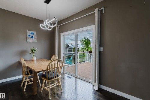 Dining area with wood-finish flooring and direct deck access through a sliding glass door - 21223 58 Avenue, Edmonton, AB 