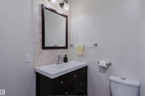 Bathroom vanity with a dark wood finish and a white integrated sink, complemented by a rectangular framed mirror - 21223 58 Avenue, Edmonton, AB 