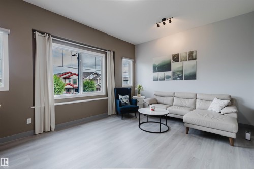 Living area featuring light wood-finish flooring, neutral paint tones, and white trim - 21223 58 Avenue, Edmonton, AB 