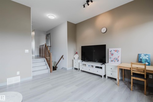 Expansive living area with light-toned wood-finish flooring, neutral wall colors, and recessed lighting - 21223 58 Avenue, Edmonton, AB 