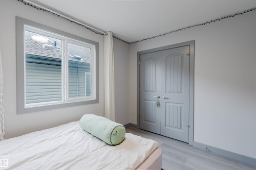 Room featuring light gray walls, gray wood-finish flooring, a double window with gray trim, and a double-door closet with paneling - 21223 58 Avenue, Edmonton, AB 