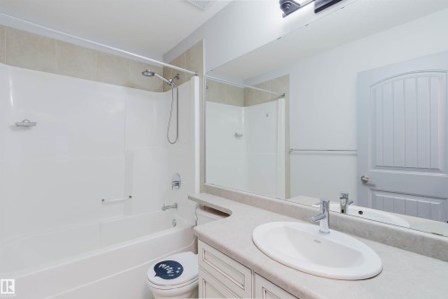 Bathroom featuring a built-in tub and shower combination with a curved shower rod and tiled surround - 21223 58 Avenue, Edmonton, AB 