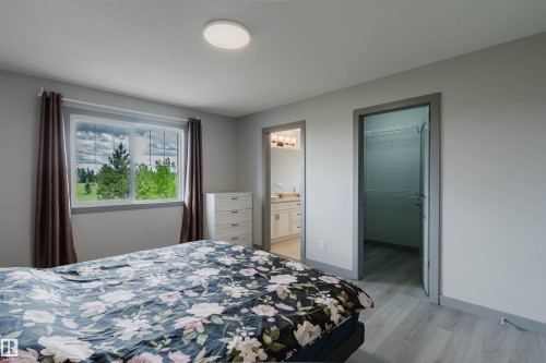 Inviting room featuring a large window with white trim, wood-finish flooring, and a contemporary ceiling light fixture - 21223 58 Avenue, Edmonton, AB 