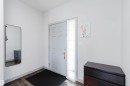Entryway featuring a paneled door with a sidelight, wood-finish flooring, and light-toned walls - 21223 58 Avenue, Edmonton, AB 