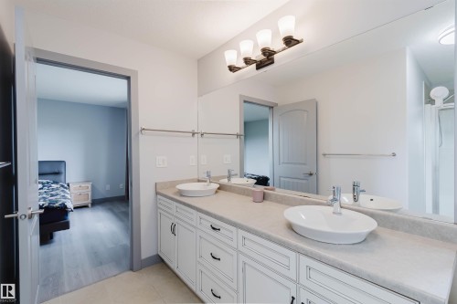 Bathroom featuring a double vanity with white cabinetry, vessel sinks, and an expansive mirror - 21223 58 Avenue, Edmonton, AB 