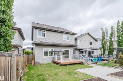 Rear exterior featuring a two-story design with light gray siding, a composite deck with white railings, and a ground-level patio - 21223 58 Avenue, Edmonton, AB 