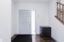 Entryway featuring a paneled door with sidelight, wood-finish flooring, and a light wood-toned staircase with balusters - 21223 58 Avenue, Edmonton, AB 