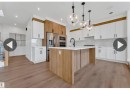 Modern kitchen featuring an island with a light wood-finish base and white countertop, white upper and lower cabinetry, and complementary wood-finish cabinetry - 13140 187 Avenue, Edmonton, AB 