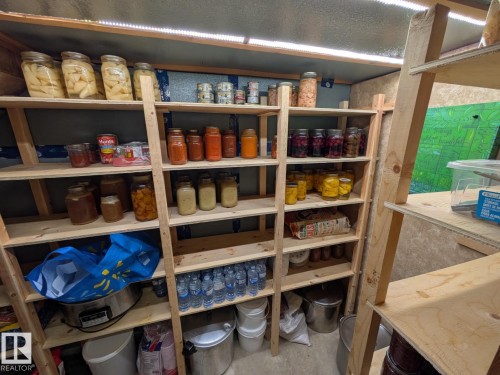 Custom-built shelving system featuring multiple tiers of storage, integrated strip lighting, and a durable concrete floor - 4208 89 Street, Edmonton, AB - Indoor With Storage