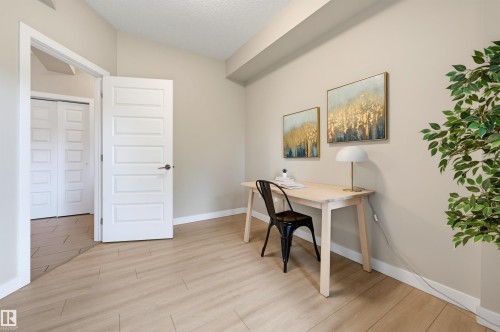 Light wood-finish flooring complements neutral wall tones - 115 1238 Windermere Way, Edmonton, AB 