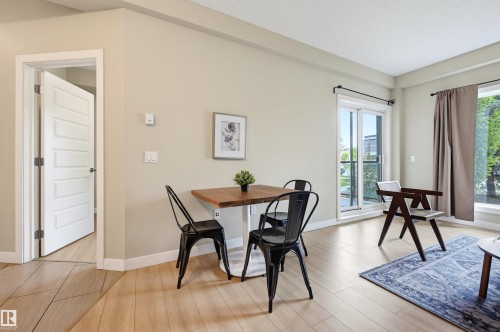 Hardwood-finish flooring throughout, featuring a sliding glass door to an exterior space, and a large window providing abundant natural light - 115 1238 Windermere Way, Edmonton, AB 