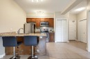Kitchen featuring granite countertops, stainless steel appliances, wood cabinetry, and a breakfast bar - 115 1238 Windermere Way, Edmonton, AB 