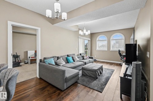 Spacious living area featuring wood-finish flooring and vaulted ceilings - 402 8730 82 Avenue, Edmonton, AB 