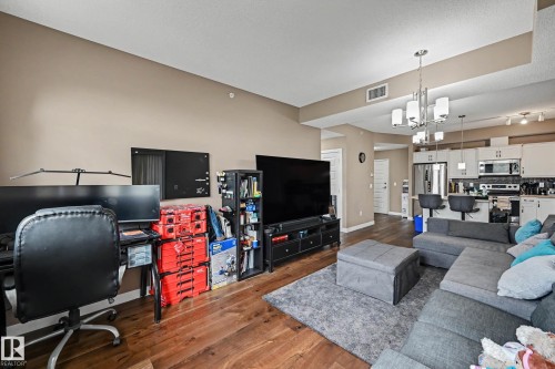 Open-concept living area featuring wood-finish flooring and neutral-toned walls - 402 8730 82 Avenue, Edmonton, AB 