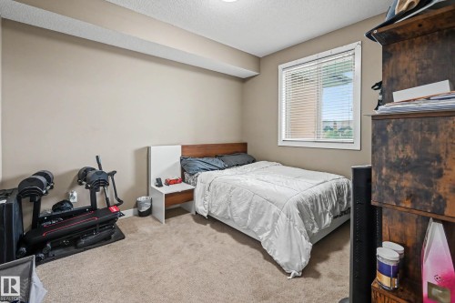 Carpeted room featuring a window with white blinds, neutral wall paint, and a textured ceiling - 402 8730 82 Avenue, Edmonton, AB 