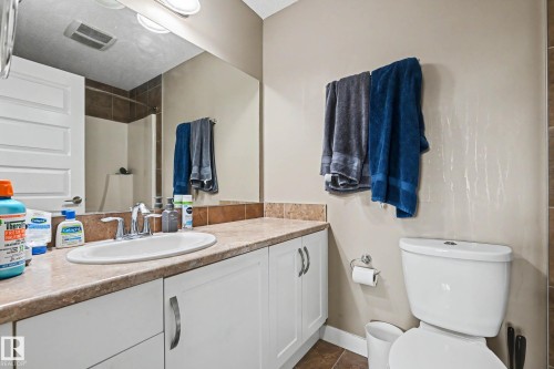 Vanity with an integrated oval sink and a light-toned countertop, complemented by a large mirror and overhead lighting - 402 8730 82 Avenue, Edmonton, AB 