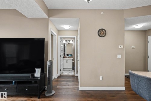 Interior hallway and wall featuring dark wood-finish flooring, light tan painted walls, white baseboards, and white ceiling - 402 8730 82 Avenue, Edmonton, AB 