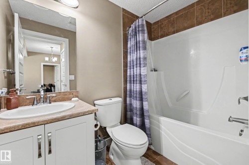 Full bathroom featuring a single vanity with an integrated sink, a commode, and a tub-shower combination - 402 8730 82 Avenue, Edmonton, AB 