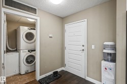 Dedicated laundry area with stacked washer and dryer, adjacent to an entry door with five horizontal panels - 