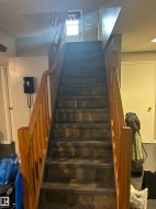 Staircase with wood-finish handrails and banisters, featuring stone-look tile treads and painted risers - 