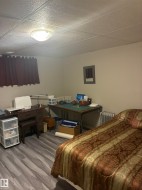 Spacious room featuring wood-finish flooring, a drop ceiling with recessed lighting, and neutral wall paint - 