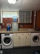 Laundry area featuring a front-loading washing machine, built-in cabinetry with silver hardware, and a laminate countertop - 