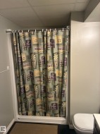 Enclosed shower stall with white base and curtain rod - 