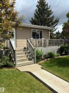 Exterior featuring horizontal siding, a spacious wooden deck with railings, sliding glass patio doors, and a concrete walkway - 