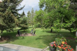 Expansive green lawn featuring a paver patio with a central fire pit - 