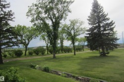 Expansive green lawn with mature trees and a gravel pathway - 