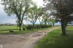 Gravel driveway bordered by mature trees and manicured lawn - 