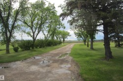 Gravel driveway bordered by manicured lawns and mature trees - 