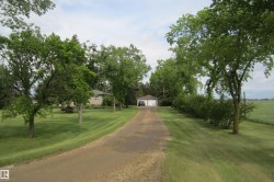 Long gravel driveway leading to a detached garage with two white overhead doors - 
