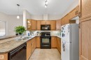 U-shaped kitchen featuring light wood cabinetry, stone-finish countertops, and tile flooring - 133 2503 Hanna Crescent, Edmonton, AB 
