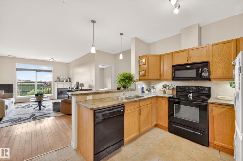 Kitchen featuring wood cabinetry, black appliances, and a double basin sink - 133 2503 Hanna Crescent, Edmonton, AB 