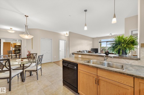 Kitchen featuring wood-finish cabinetry, a double basin stainless steel sink, and a black dishwasher - 133 2503 Hanna Crescent, Edmonton, AB 
