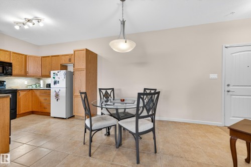 Kitchen and dining area featuring light wood cabinetry, black appliances, tile flooring, and a contemporary ceiling light fixture - 133 2503 Hanna Crescent, Edmonton, AB 