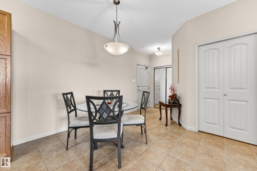 Dining area featuring neutral wall tones, tile flooring, a chandelier with frosted glass, and white bi-fold doors - 133 2503 Hanna Crescent, Edmonton, AB 