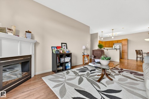 Living area featuring wood-finish flooring, a white mantel fireplace, and neutral wall tones - 133 2503 Hanna Crescent, Edmonton, AB 