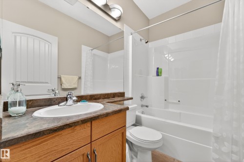 Bathroom featuring a light wood-finish vanity with a dark countertop and undermount sink, chrome faucet, and integrated mirror - 133 2503 Hanna Crescent, Edmonton, AB 