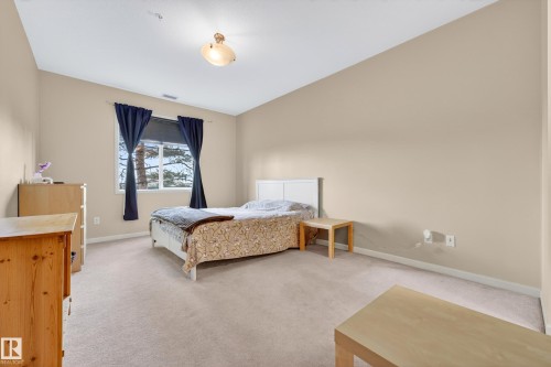 Carpeted room featuring neutral wall tones, a large window with natural light, and a ceiling-mounted light fixture - 133 2503 Hanna Crescent, Edmonton, AB 