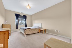 Carpeted room featuring neutral wall tones, a large window with natural light, and a ceiling-mounted light fixture - 