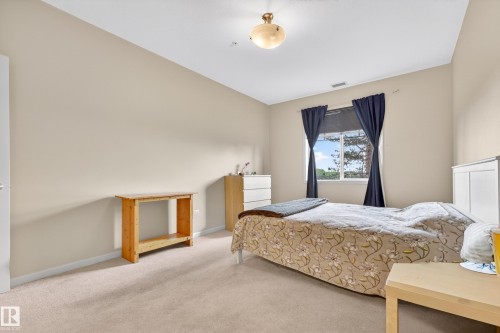 Spacious bedroom featuring light neutral wall paint, a window with exterior tree views, and wall-to-wall carpeting - 133 2503 Hanna Crescent, Edmonton, AB 