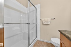 Shower enclosure with sliding glass doors, integrated shelving, tiled flooring, and a towel bar - 